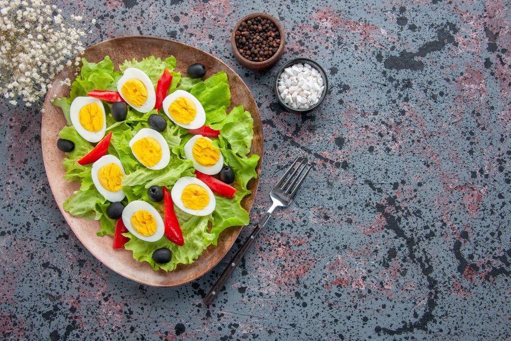 Quick and Easy Healthy Lunch Recipes | 5-Minute Meals for Busy Days 1 Healthy Lunch Recipes: Healthy salad with lettuce, boiled eggs, black olives, and red bell peppers on a rustic plate, served with seasoning.