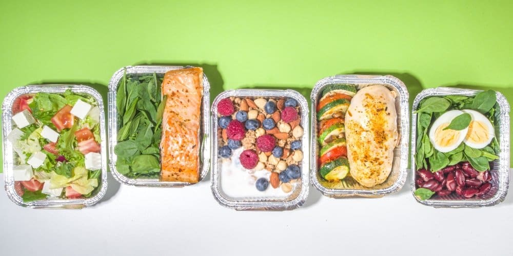 30g Protein Lunch Ideas: A colorful display of healthy meal prep containers featuring 30g protein lunches, including grilled chicken, salmon, boiled eggs, beans, salads, and Greek yogurt with berries.