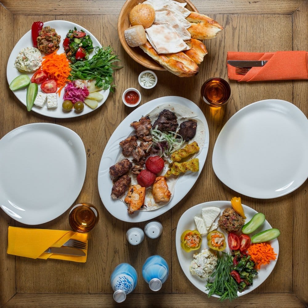 What to Feed 20 People for Lunch: Delicious & Easy Ideas 3 What to Feed 20 People for Lunch: "Traditional Mediterranean meal with grilled meats, fresh vegetables, salads, and bread served on a wooden table."