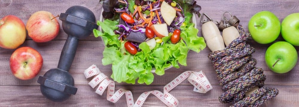 30g Protein Lunch Ideas: Quick and Delicious Meals 3 30g Protein Lunch Ideas: A healthy lifestyle flat lay with fresh apples, a colorful salad bowl, a dumbbell, a jump rope, and a measuring tape on a wooden background.