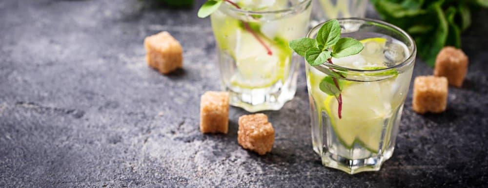 Hugo Spritz Recipe – A Refreshing Summer Cocktail 2 Two glasses of Hugo Spritz garnished with fresh mint and lime, surrounded by sugar cubes on a rustic dark table.