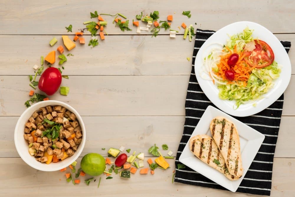 The Best Lunch Ideas for Busy Weeknights: A healthy lunch setup featuring grilled chicken breast, fresh vegetable salad, and a bowl of tofu stir-fry on a wooden table with vibrant ingredients.